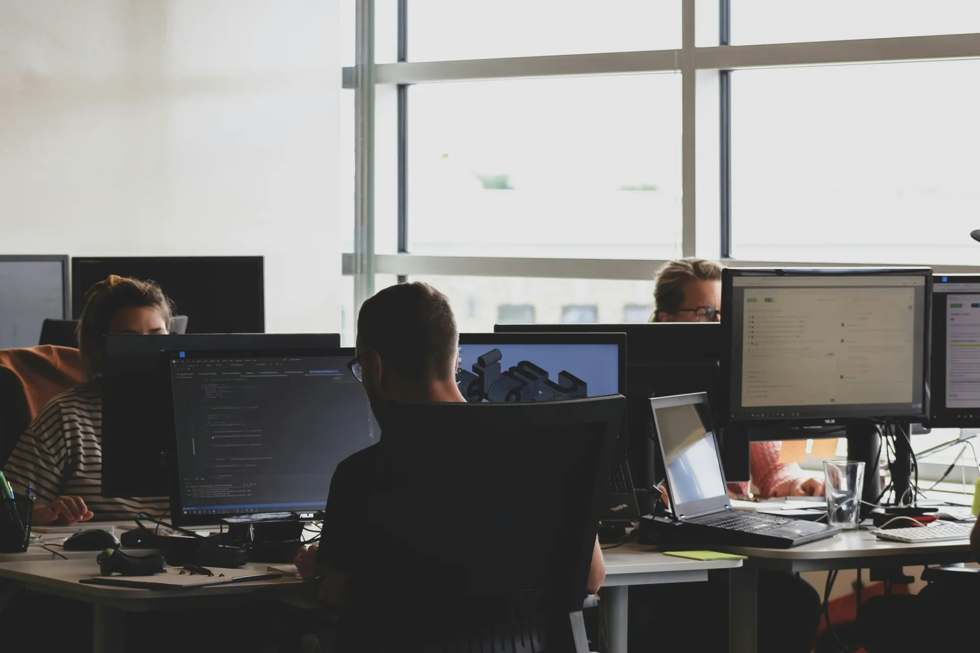 Developers at work in front of multiple screens
